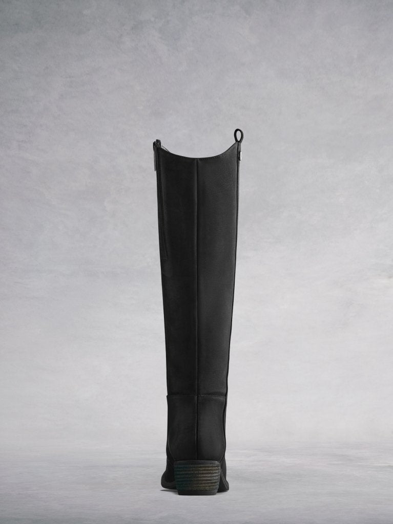 Staple boot with a curved topline and a low stacked leather veneer heel.
