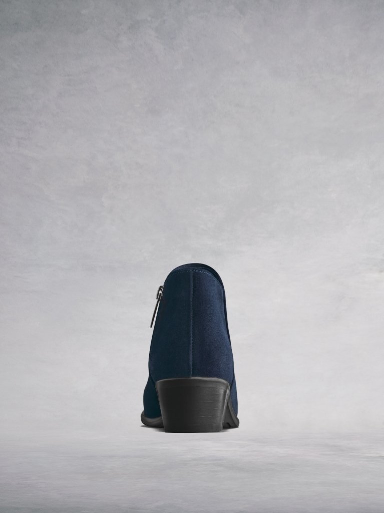 The low cut navy ankle boot has a flattering curved topline. 