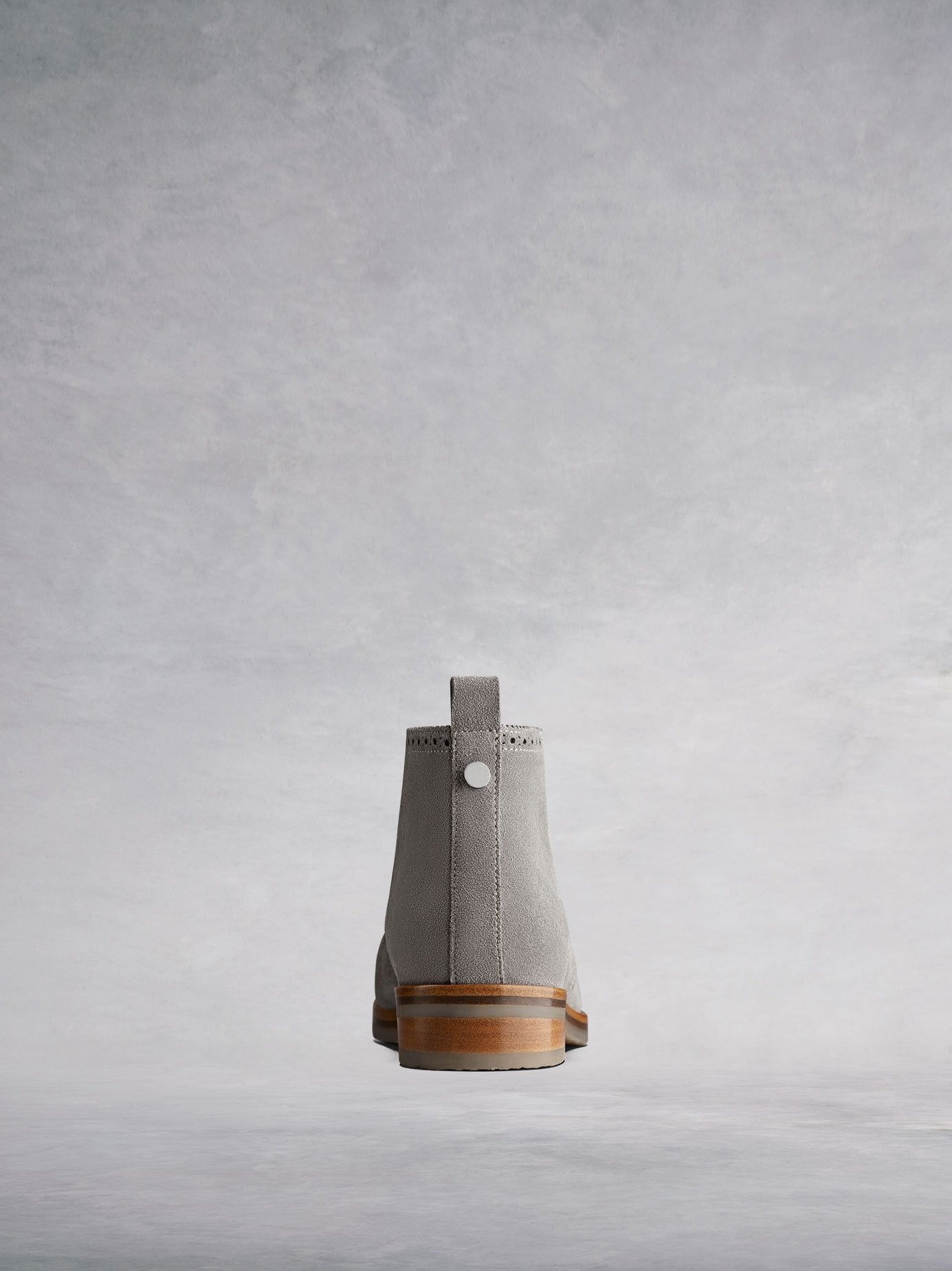 This grey chukka boot has a pull tab and stud detailing.