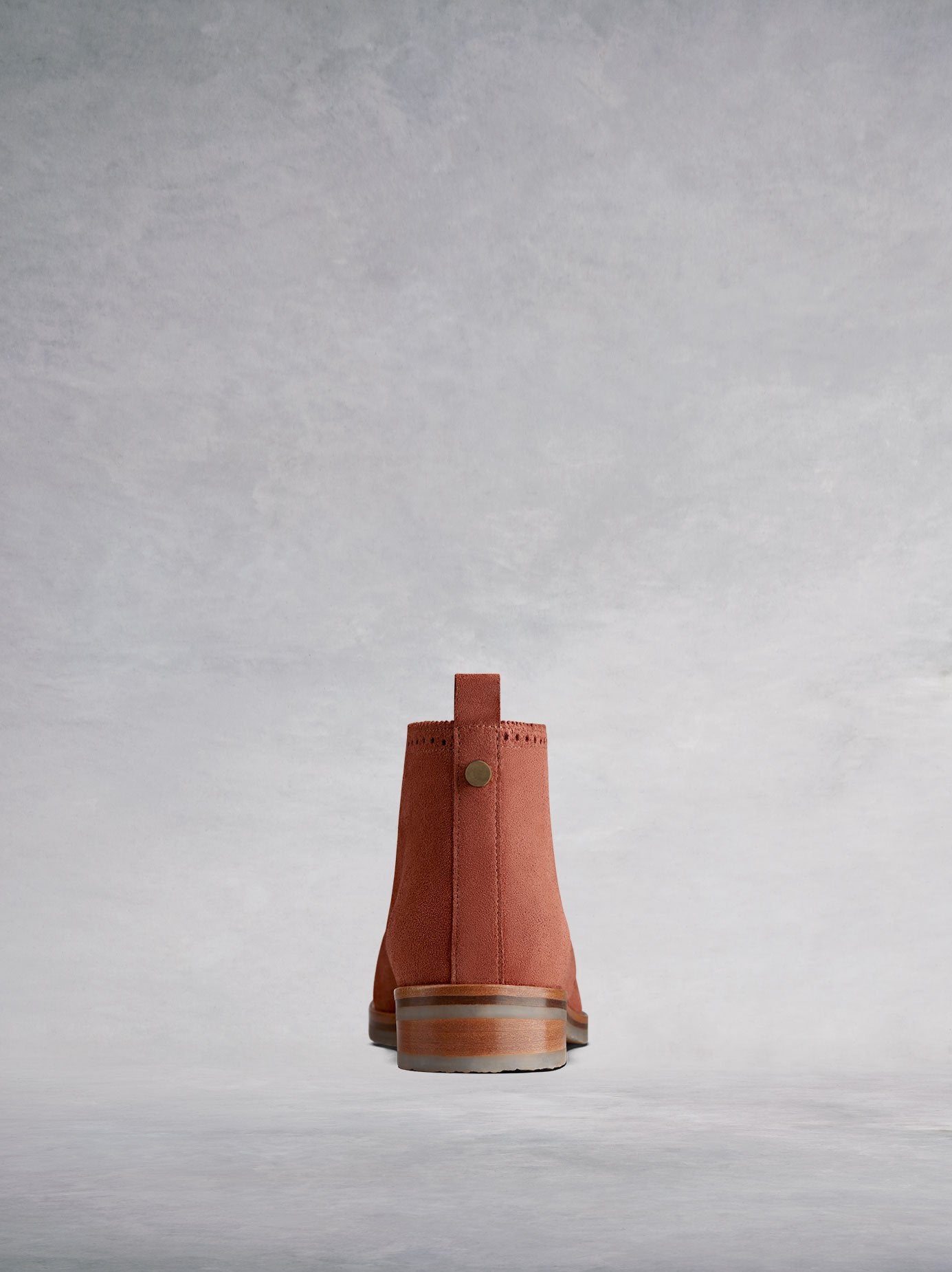 This tan chukka boot has a pull tab and stud detailing.