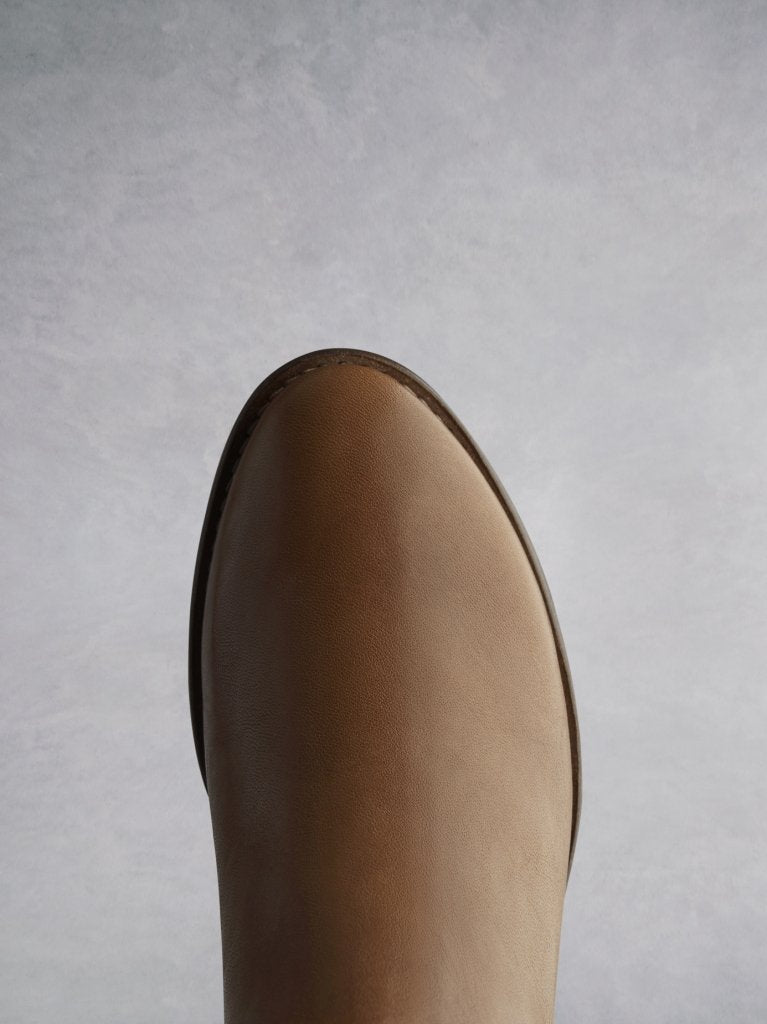 The tan almond shaped toe complements the western inspired styling. 