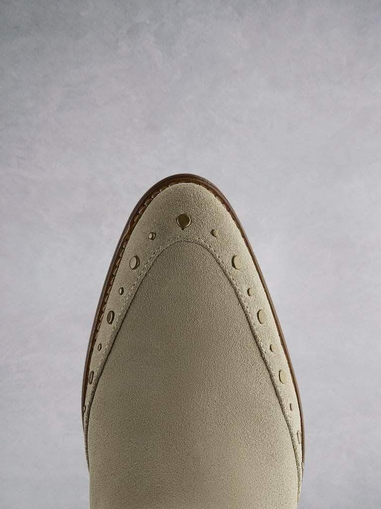 Emilia in taupe suede, featuring stud detailing that highlights the almond toe shape.