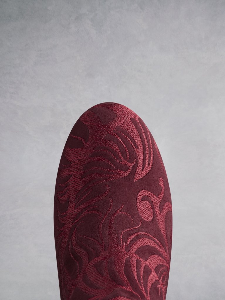 The round burgundy suede toe is covered in tonal embroidery. 