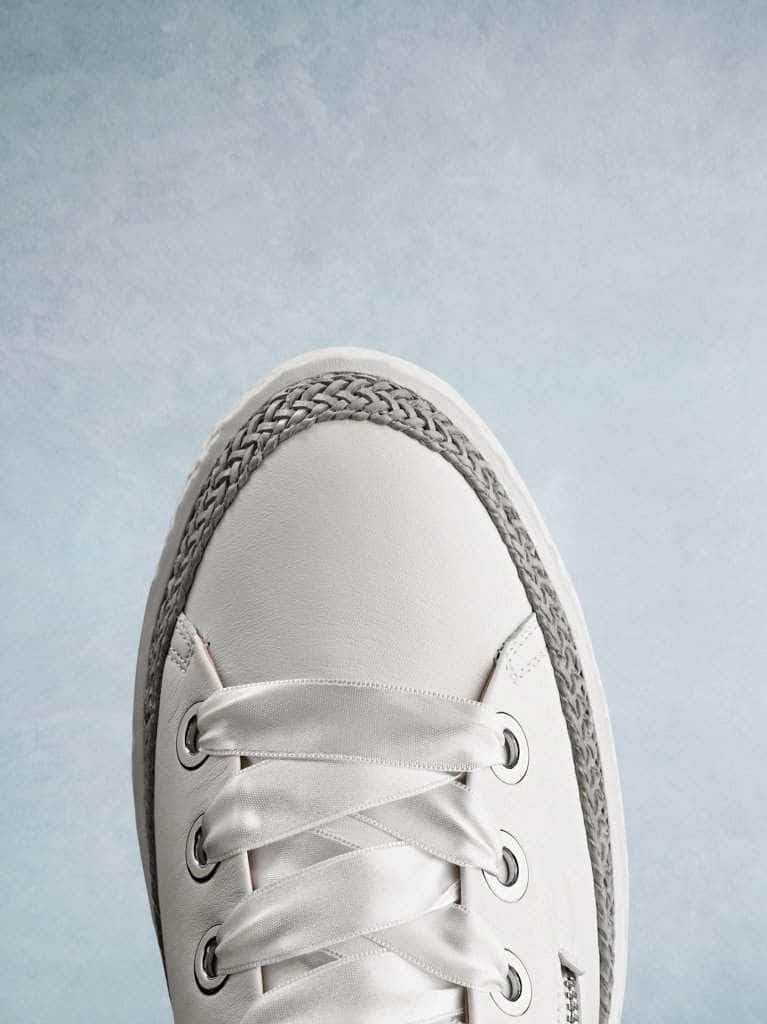 This white leather trainer has a smooth round toe highlighted by the lace trim.