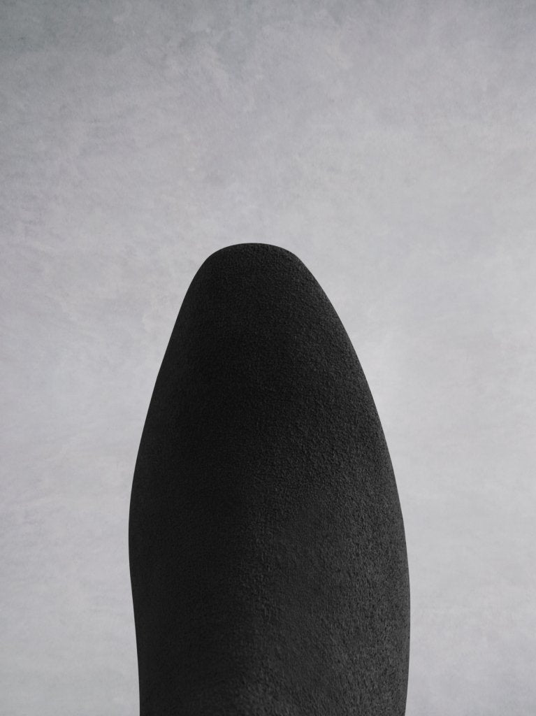 The black suede boot has a chisel toe shape that matches the heel shape.