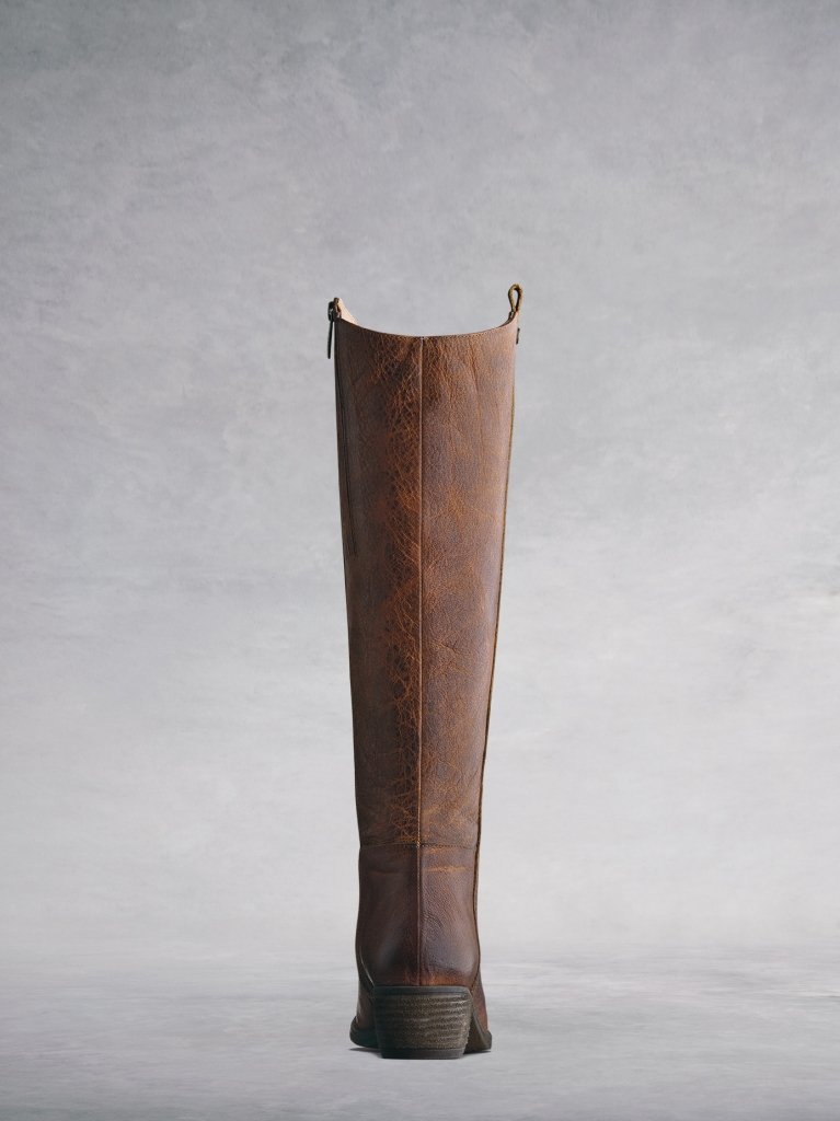 Staple boot with a curved topline and a stacked leather veneer heel. 