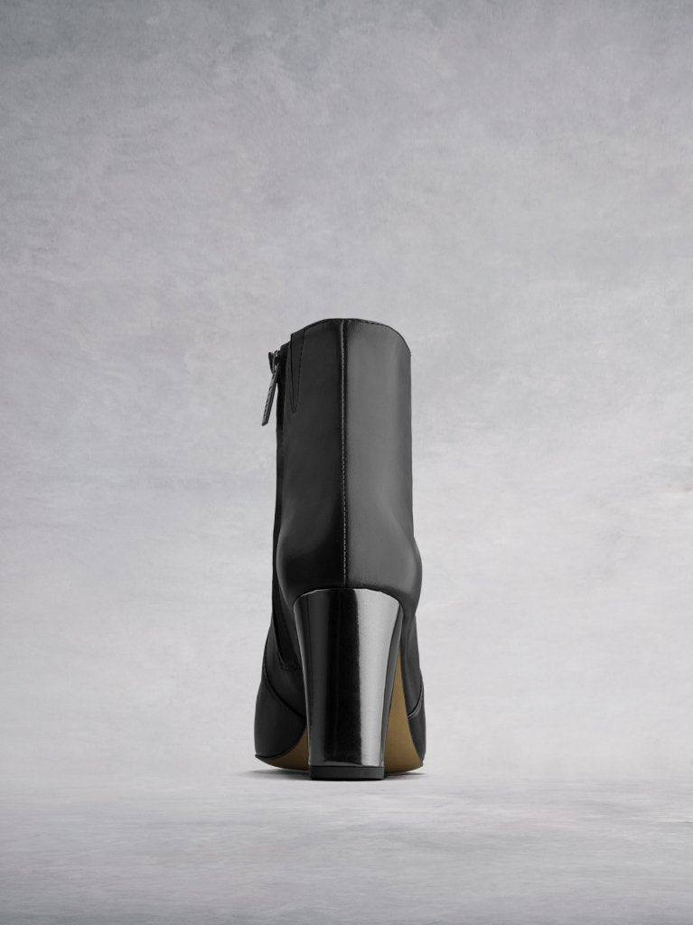The back features a contrasting metallic silver block heel with a chisel edge.